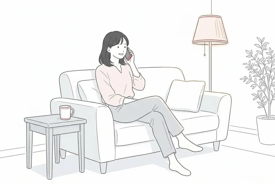 自宅のソファでリラックスしながら電話で通話を楽しむ20代後半の女性