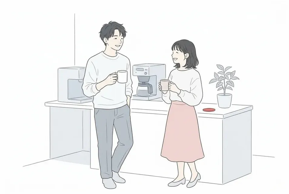 オフィスの休憩スペースでマグカップを片手に笑顔で雑談する男女の会社員